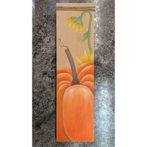 A photo of a fall pumpkin painting project that has a pumpkin and yellow flower painted on a board.