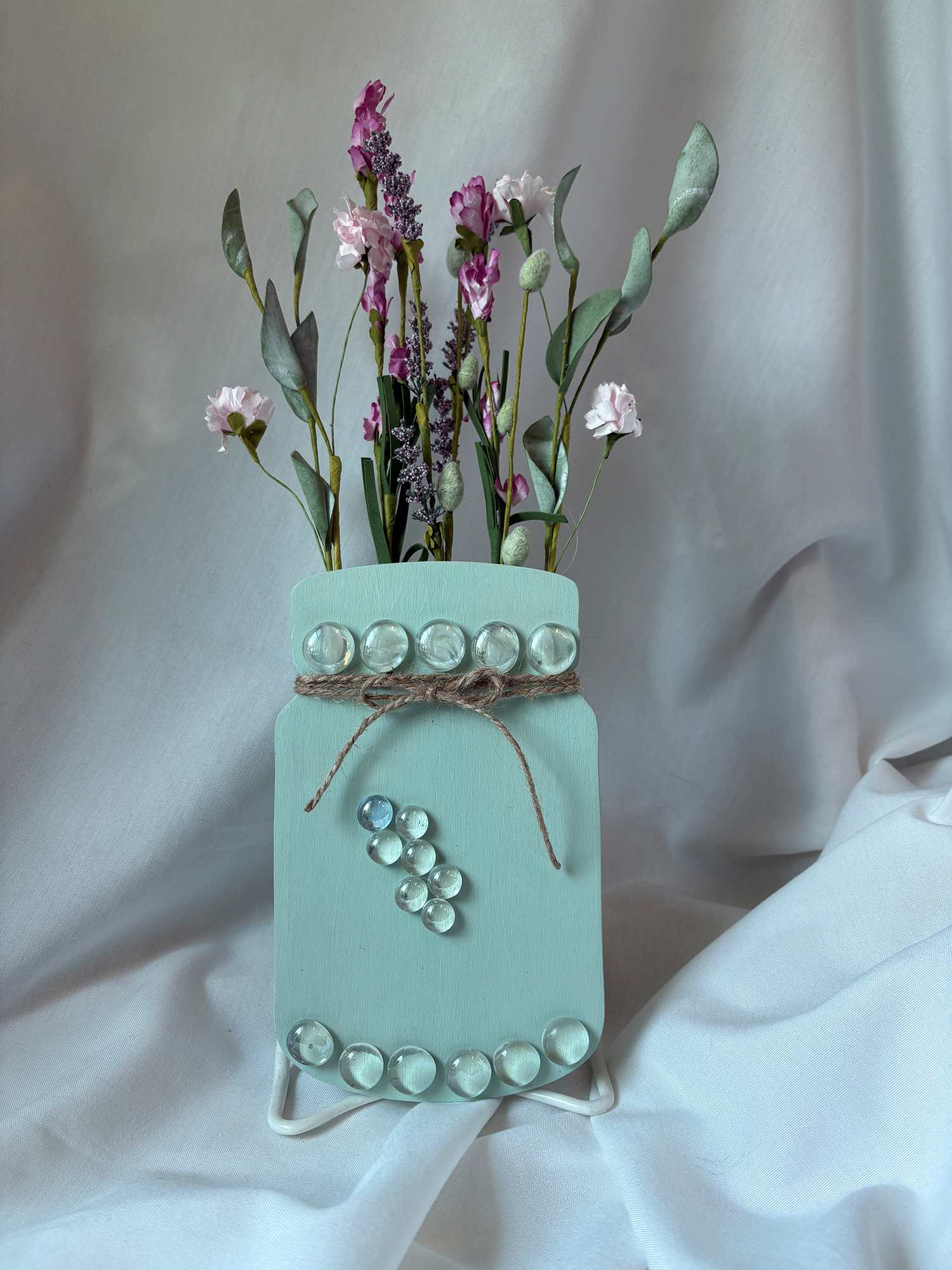 An art piece consisting of a wooden jar with dried flowers.